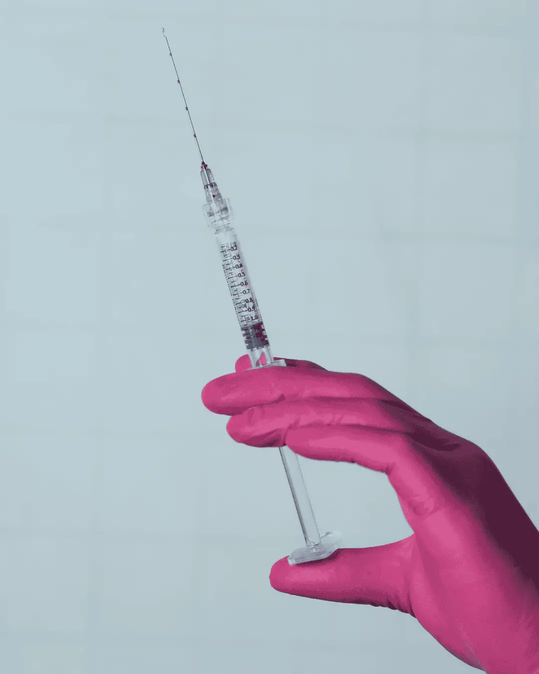 Hand in pink medical glove holding a syringe, symbolizing ScroTox treatment for men's aesthetic wellness at Prime Vitality.