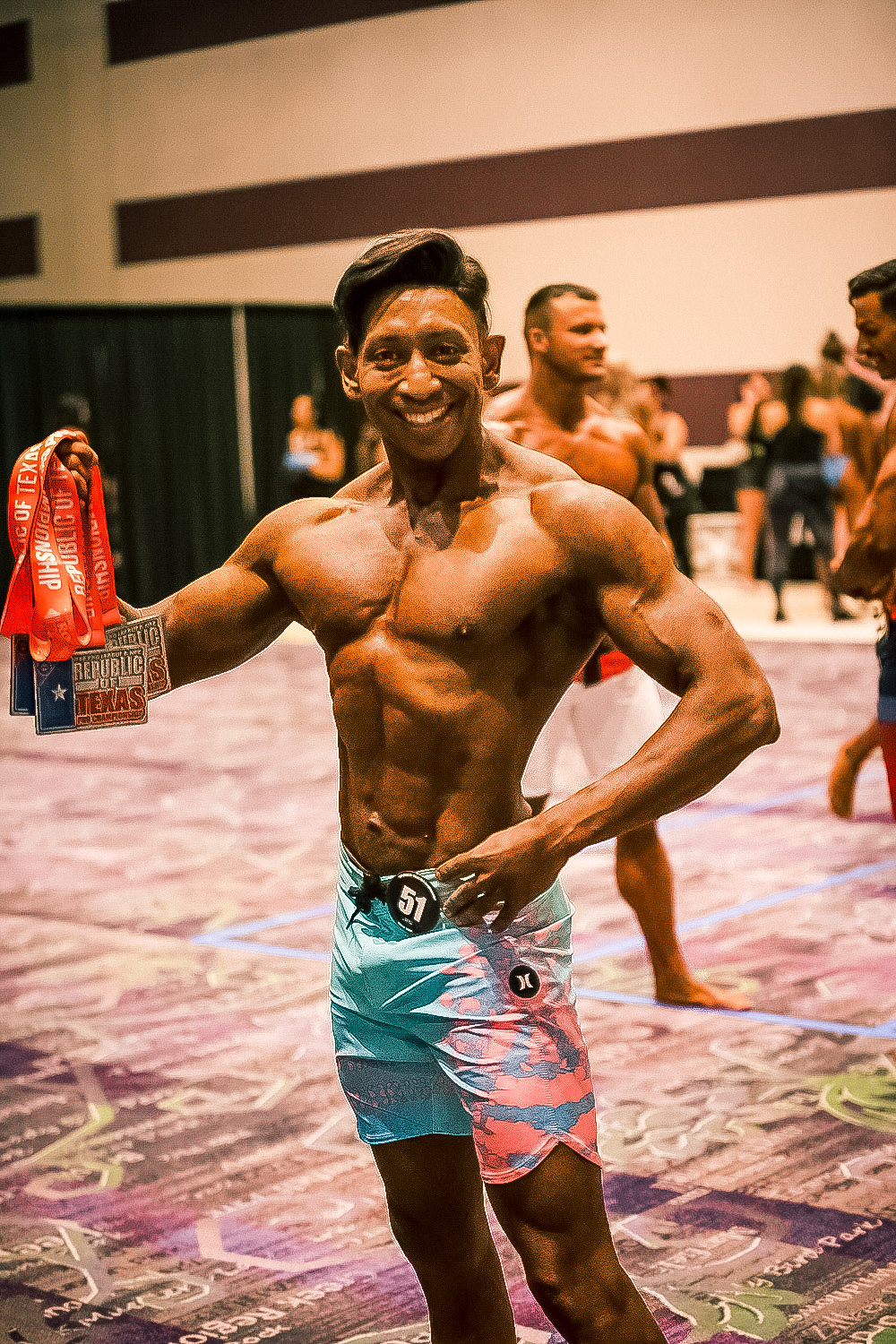 Dr. Shiv Goel celebrating backstage at the NPC Republic of Texas championship, showcasing his Men's Physique Masters medals and demonstrating elite conditioning.