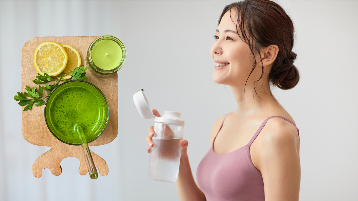 Woman smiling while holding a water bottle, with a green detox drink, lemon slices, and fresh parsley on a wooden board, emphasizing detoxification and health.