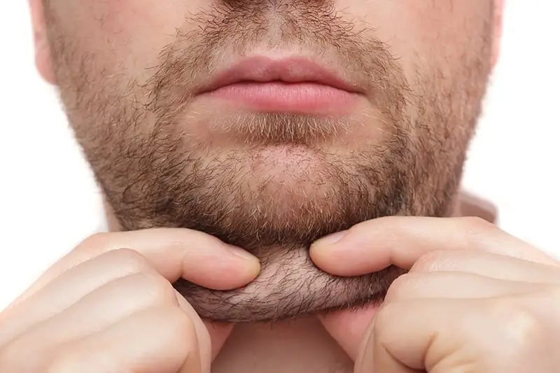 Man grasping submental fat beneath the chin, illustrating concerns related to double chin and potential treatment options at Prime Vitality Care.