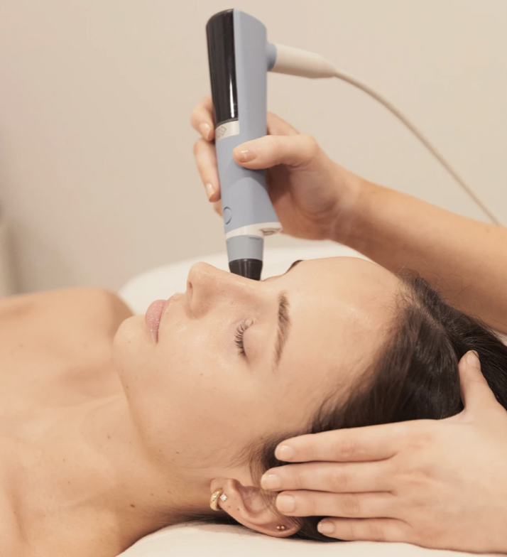 Woman receiving Exion skin tightening treatment with a handheld RF device, demonstrating advanced aesthetic technology for collagen remodeling.