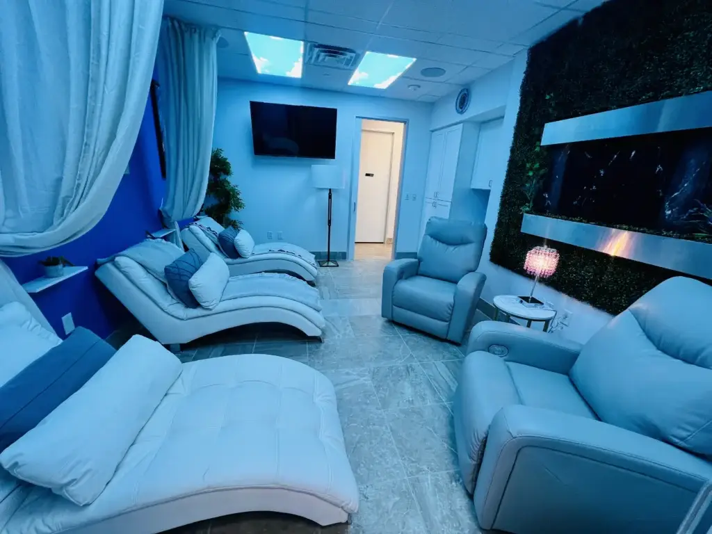 Relaxation area with lounge chairs, decorative plants, and soft blue lighting.